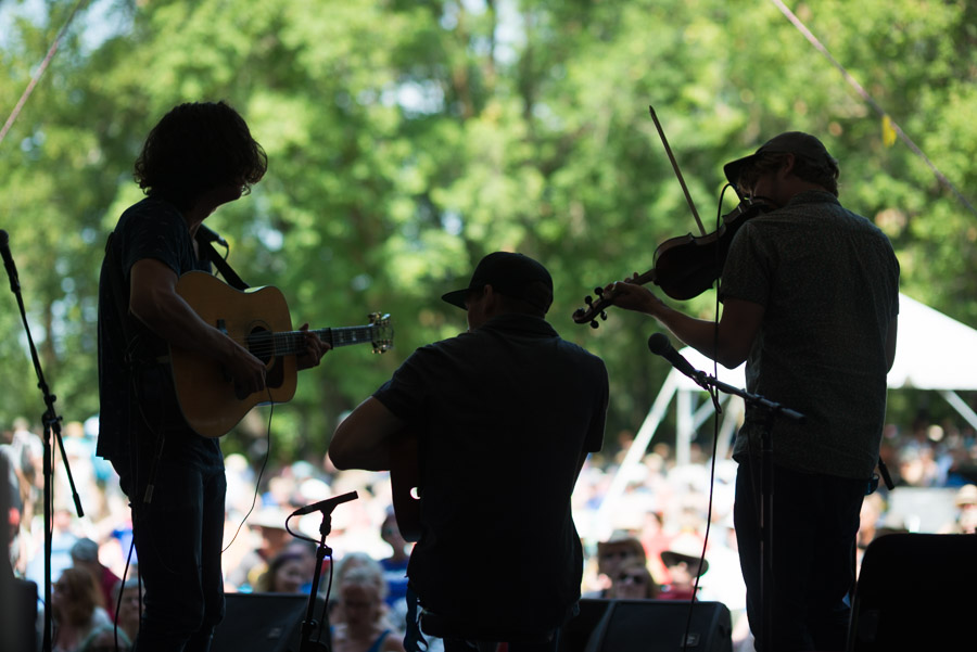 Ten Strings and a Goat Skin - add &rsquo;em up: six on a guitar, four on the fiddle, and then the drum - silhouetted against the crowd.