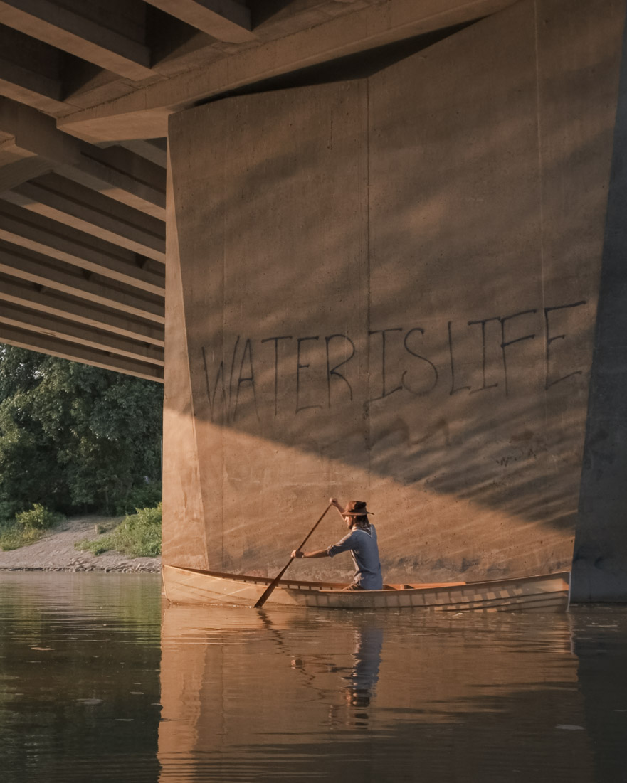 Paddling under a Winnipeg bridge emblazoned with ‘WATER IS LIFE’.