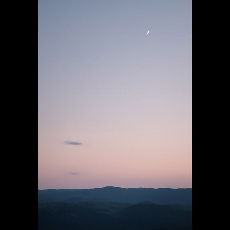 Moon rising over undulating valleys.