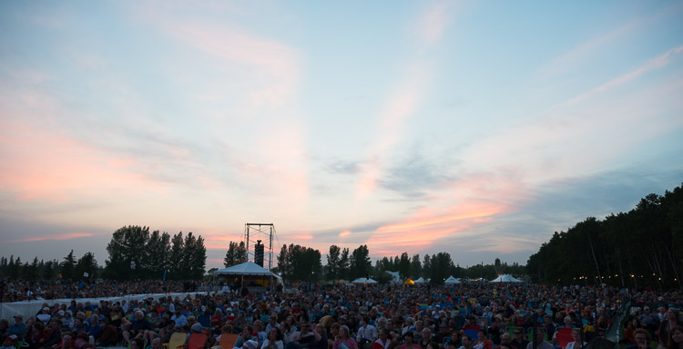 Main stage lights up as the sun sets behind the crowd. Often the artists are treated to a beautiful prairie sunset that the crowd, fixated on the entertainment, usually does not notice.