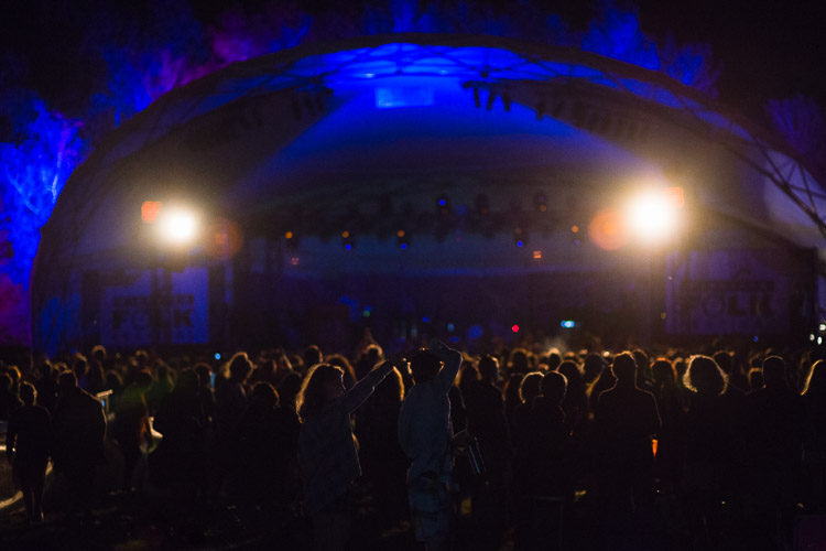 The crowd waits in anticipation of the next act lighting up the night.