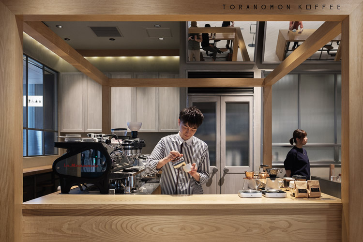 Barista Takayuki Ishitani prepares a drink behind the pale wooden counter of Toranomon Koffee in Tokyo