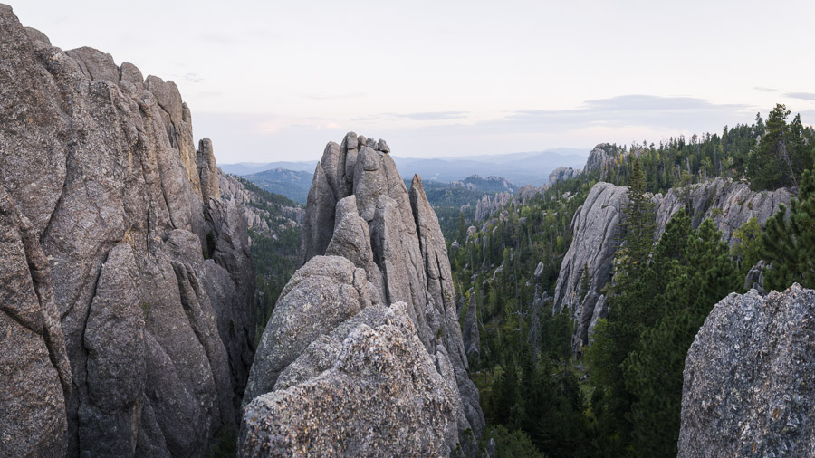 Granite spires and pine-filled valleys of the Cathedral Spires at dusk, ridges fading blue into the distance