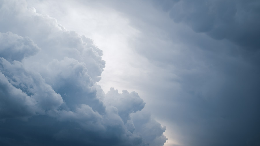 Billowing white cumulus towers building against a darkening blue-grey storm front