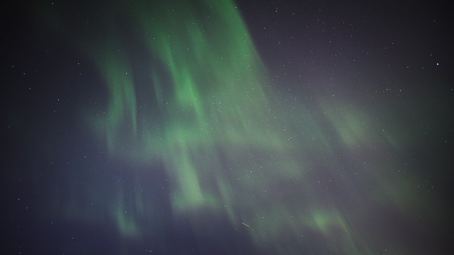 Green curtains of aurora streaking across a star-filled night sky