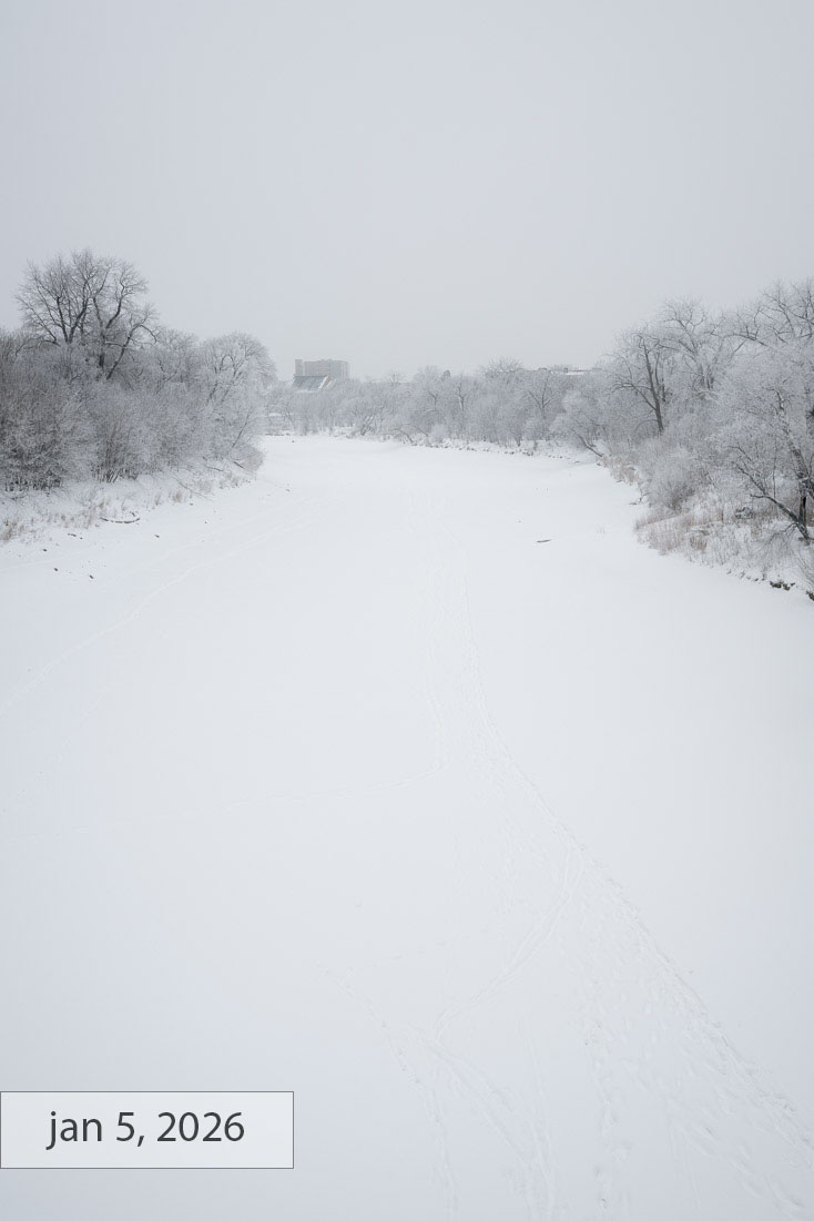 Labeled jan 5, 2026: the same river view fully frozen and white, frosted trees lining both banks under a flat grey sky